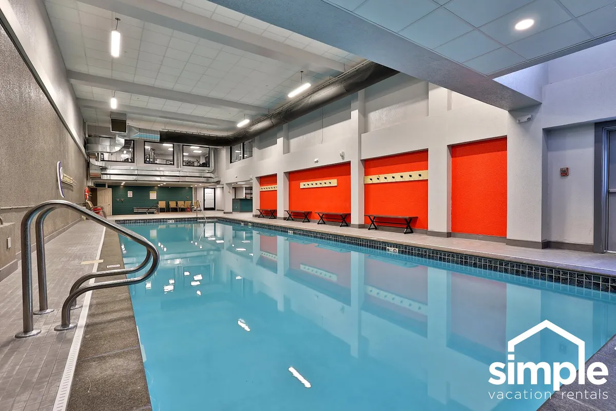 A lively indoor swimming pool with bright red walls, seating area, and inviting water—ideal for relaxation or socializing after a day on the slopes.