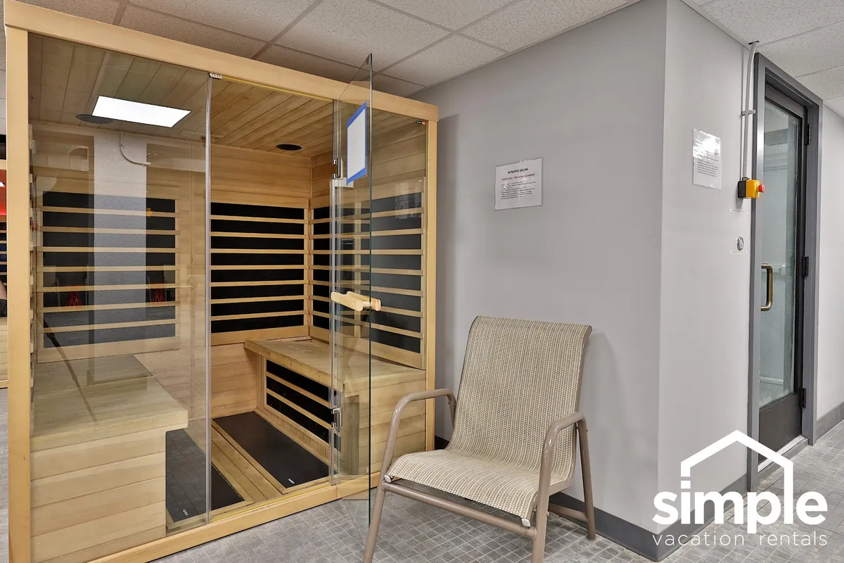 A serene interior view of a traditional sauna with wooden benches and a single lounge chair. The focus is on the warm, wood-lined interior, evoking a sense of peaceful retreat ideal for personal wellness and rejuvenation.