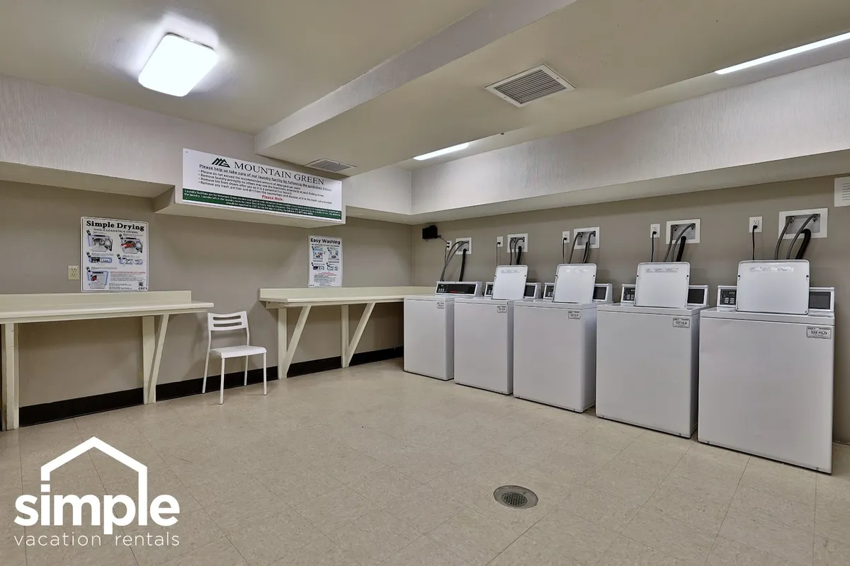 A practical laundry room featuring modern machines, counter space, and community signage—emphasizing group convenience and efficiency during extended stays.
